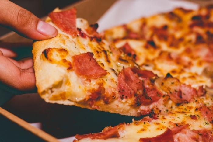 person-taking-pizza-slice-for-nyc-food-tours