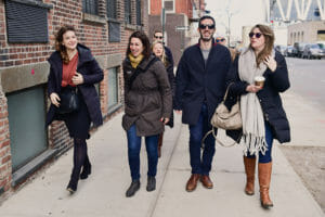guests walking on street on williamsburg food tour with bags