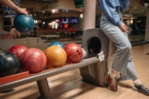 woman-leaning-on-bowling-ball-during-corporate-party